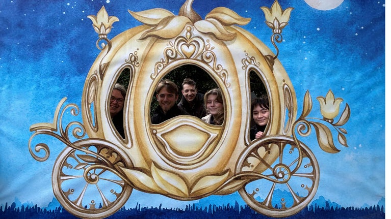 Staff peeping through the windows of a cut-out gold-coloured Cinderella carriage